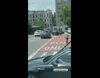Guy crossing the crosswalk with a giant cross 

