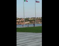 Brunette dancer films video near flag poles 