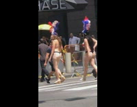 Two women in burlesque feather headpiece and thong walk on crosswalk