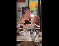 Woman films spaghetti with light inside restaurant