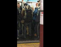Cat Wearing Cutoff Shirt Stands on Man's Backpack in Subway