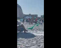 Woman in red bikini with sun visor poses at the beach