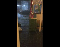 Traffic cones and garbage bags float in flood next to restaurant 