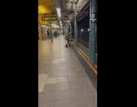 Guy wearing camo jumpsuit doing weird movements at subway platform