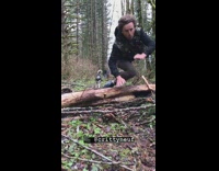 Guy runs away from dog and trips over tree log on forest floor