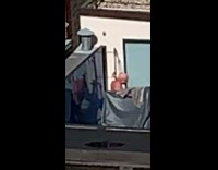 Old man takes a shower on rooftop patio with gray covers across building