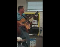 Man plays the guitar to sing and teach a Spanish song