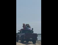 Three women top of pickup truck sings Piña Colada beach