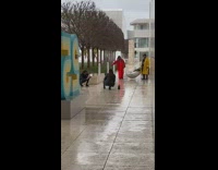 Woman in black outfit crouches in front of the blank wall