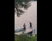 Woman in black shirt raises glass by the docks