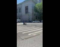Guy riding blue lawn chair with wheels down street 