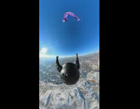 POV camera view from the helmet of a person parachuting down 
