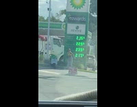 Woman dance tiktok beside gas station prices