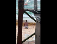 Man shirtless digs sand for beach video