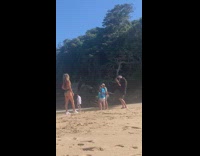 Woman in green bikini with a drink poses at the beach