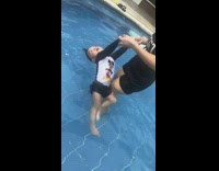 Mother helps her baby float on water in swimming pool, squeaky voice