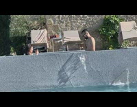 Man shirtless sunglasses walk on pool filmed by woman