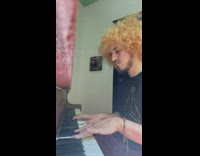 Man wearing black shirt plays piano