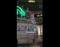 Party bus with people in colorful outfits dancing on top