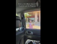 Woman walks back to car with bags and boxes of popcorn