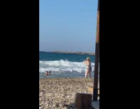 Guy sunglasses holds black bottle ocean waves