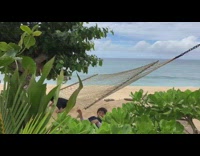 Two boys flips over on net hammock and scorpion together on sand at beach