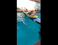 Two guys on plastic raft inside pool boxing each other