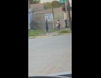 Man gray top dances in front of a woman at the sidewalk