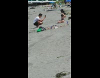Woman in gray bikini kneels at the beach sand