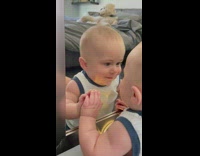Baby fascinated by own reflection in mirror