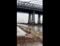 Dirty flood water flows underneath the bridge