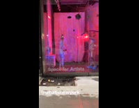 Two people wearing silver bodysuits pool noodles