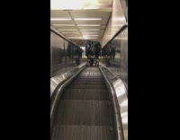 Person struggles to move cart down escalator 