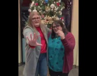 Two women directing man to take picture xmas tree