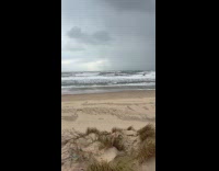 Man with surfboard run towards large waves