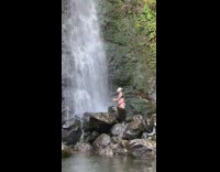 Girl posing bottom of waterfall black rocks