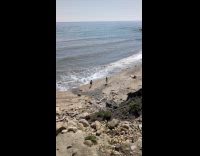 Two women films candid video at beach