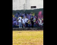 Three guys  film rap video beside graffiti