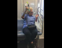 Woman in blue shirt plays bop it toy game on subway train