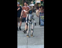 Rizzbot walking on sidewalk with security chaperone pt. 2