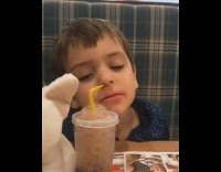 Kid blowing bubbles into cup with nose through yellow straw