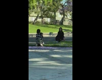 Girl squats on grass purple jacaranda tree 