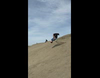 Guy backflip twists off back cliff and lands in sand 