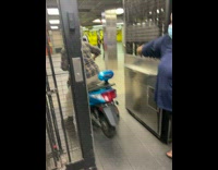 Guy walks on top of blue scooter at station 
