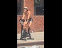 Shirtless man ride stationary bike street sunny