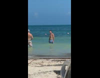 Blue shorts guy poses ocean water girl