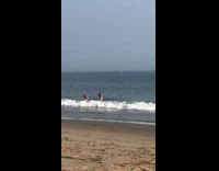 Two girls stand ocean seaweed large wave 