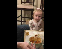 Baby makes an angry face while she eats