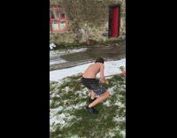 Kid in swimming trunks and orange sunglasses dives into a pile of snow