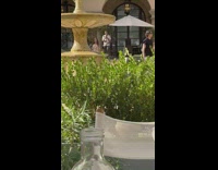 Woman in floral dress models and walk near the water fountain